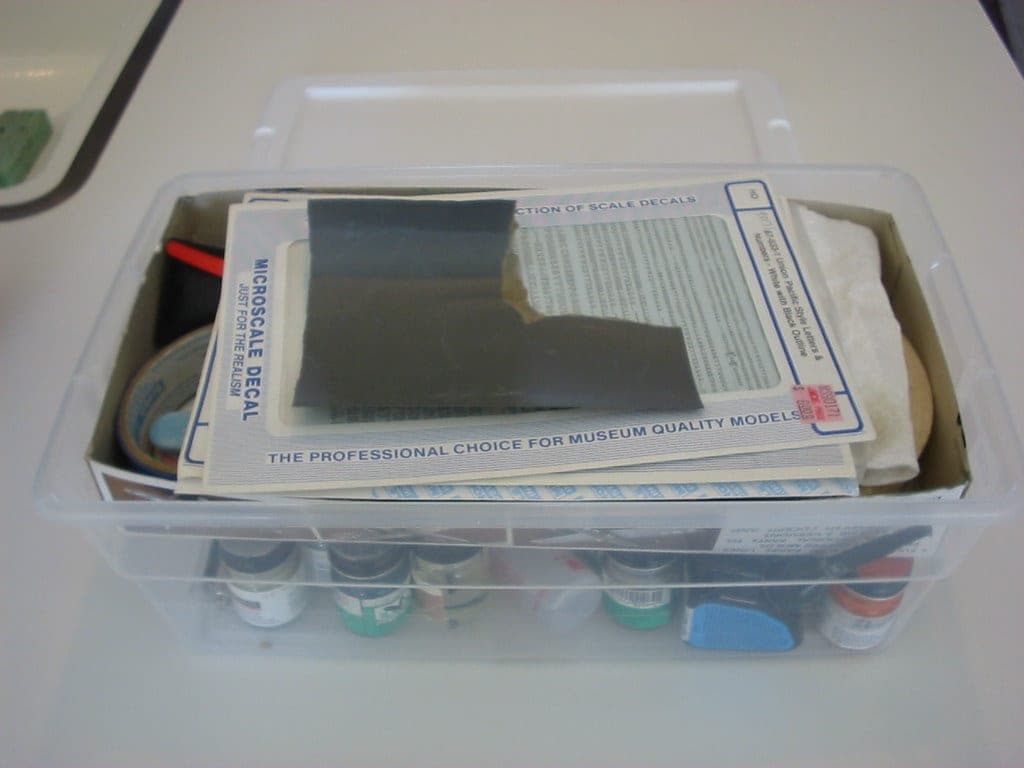 A bottle of plastic cement with a fine applicator brush